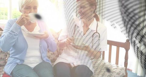 Senior woman and nurse sipping tea, chatting in sunlit homecare companion moment