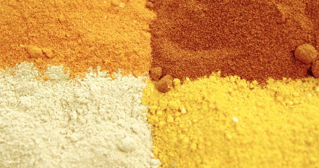 Various colorful spices are displayed in a close-up view, showcasing their textures and hues. Spices like these are essential in culinary arts, adding flavor and color to dishes around the world.