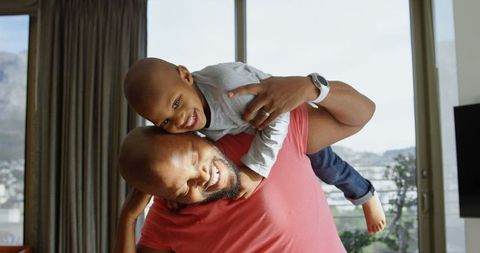 Father Piggybacking Happy Son in Home, Bonding Fun Time