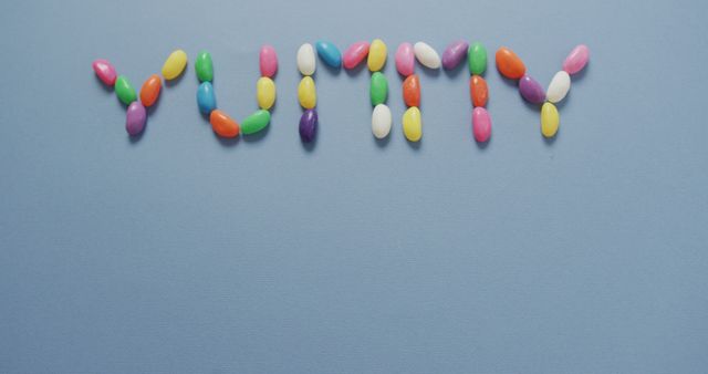 Colorful Jelly Beans Forming the Word 'Yummy' on Blue Background - Download Free Stock Images Pikwizard.com