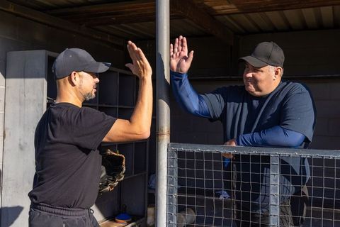 Veteran teammates high-fiving in baseball dugout showing camaraderie and team spirit