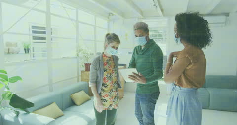 Business Colleagues Discuss Work While Wearing Masks in Bright Office