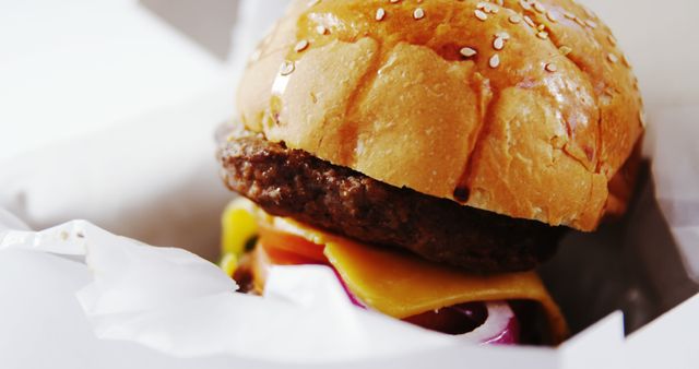 Mouth-watering close-up of a cheeseburger with a juicy beef patty, and fresh ingredients in a sesame seed bun. Ideal for promotions on fast food menus, restaurant advertisements, food blogs, and online ordering platforms.