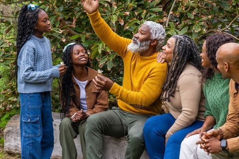 Multigenerational african american family enjoying park moment, sharing flowers and laughter