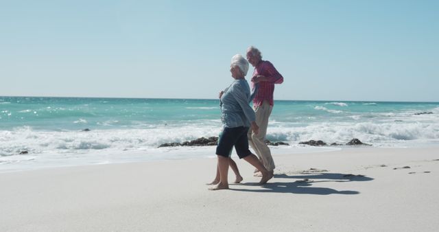 Senior Couple Enjoying Walk On Sandy Beach By Ocean Under Clear Blue Sky - Download Free Stock Images Pikwizard.com