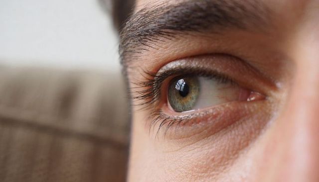 Close-up green-hazel eye showing detailed eyelashes and corneal reflection, macro portrait