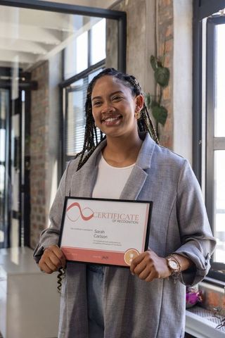 Confident woman holding achievement certificate in modern office