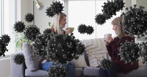 Women chatting indoors amid viral particles overlay