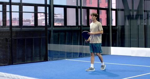 Focused Male Athlete Playing Padel Tennis on Modern Court