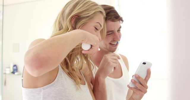 Couple Brushing Teeth Together and Looking at Phone - Download Free Stock Images Pikwizard.com