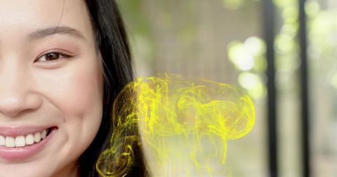 Smiling chinese woman wearing dark top looking at camera with luminous yellow hologram
