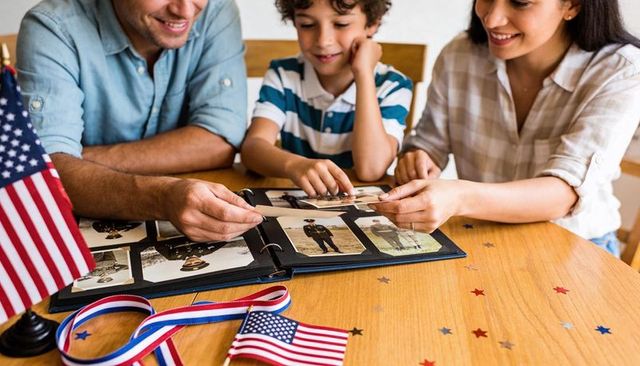 Family remembering veteran while flipping through military picture album with american flags