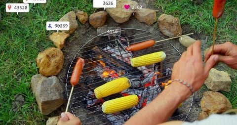 Friends grilling corn and hot dogs over rustic backyard fire
