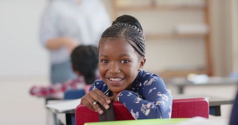 Smiling student leaning over desk in classroom environment