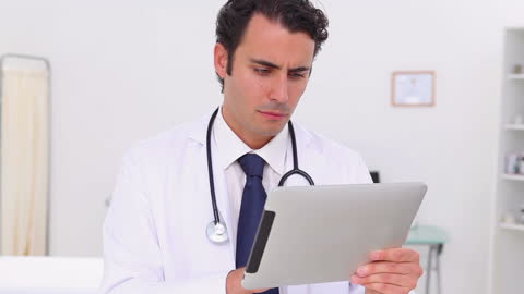 Focused Doctor Reviewing Patient Data on Tablet