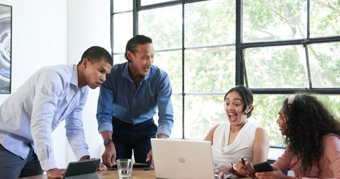 Diverse Team Joyfully Celebrating Success in Bright Office Meeting