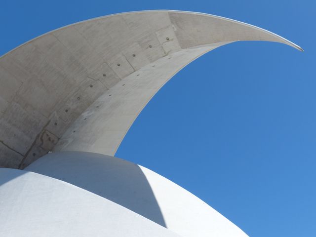 Image showcases a modern architectural detail with a curved concrete structure set against a clear blue sky. Ideal for use in architectural design presentations, urban planning visuals, and educational materials on contemporary building techniques.