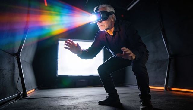 Senior man wearing vr headset reaching rainbow light beam for virtual reality immersion