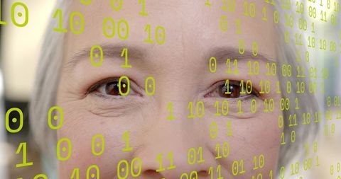 Gazing senior Asian woman closeup with neon binary overlay conveying digital identity, aging