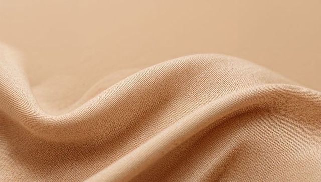 Beige knit fabric draping with soft folds close-up texture for textile design