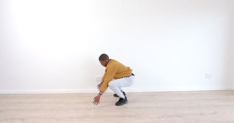 Young Man Performing Squats in Minimalist Room for Fitness - Download Free Stock Images Pikwizard.com