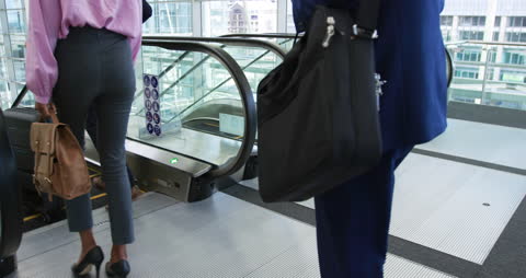 Business Professionals Descending Escalator in Modern Office Lobby