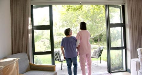 Caregiver Assisting Senior Woman at Home Up to Garden