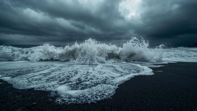 Dramatic storm wave crashing on black sand beach under heavy dark clouds coastal surf
