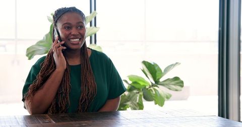 Smiling woman engaged in phone call at modern workplace