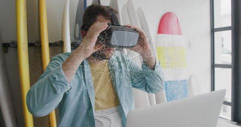 Man Experiencing Virtual Reality Amid Surfboards in Workshop