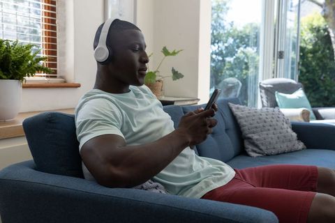 Relaxed man using smartphone with headphones at home
