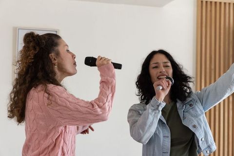 Women singing duet at home karaoke rehearsal with wireless microphones