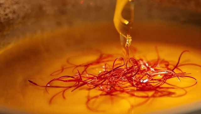 Pouring golden saffron infusion over red threads closeup macro drizzle