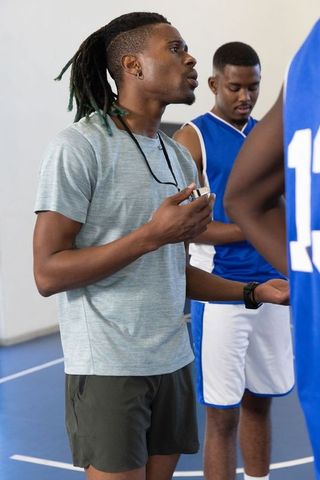Basketball Coach Training Players on Court with Stopwatch