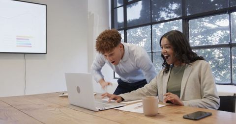 Excited Office Team Celebrating Successful Project on Laptop