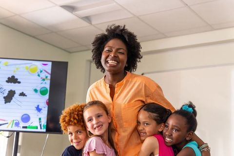 Teacher hugging smiling elementary students during classroom celebration and learning moment
