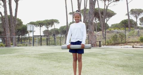 Young Girl Holding Exercise Mat on Outdoor Turf