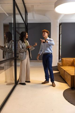 Diverse coworkers collaborating and gesturing in modern office lobby