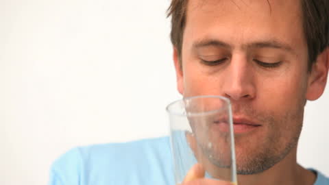 Man Savoring Refreshing Orange Juice Against Clean Abstract Background