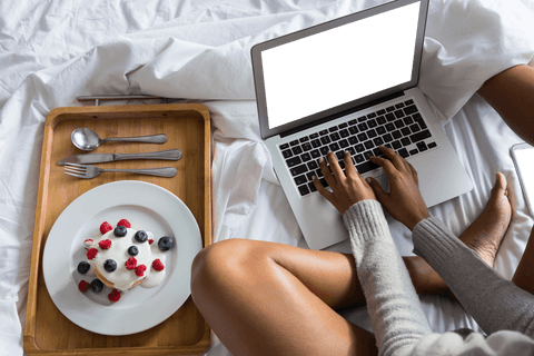 setting indicates a relaxed and comfortable morning at home. shows a person using a laptop while enjoying a breakfast of fruits on a plate in a cozy, inviting space. suitable for promoting a remote work lifestyle, relaxing weekend ideas, or leisurely breakfast-time scenes. ideal for blogs focused on work-from-home tips or cozy kitchen settings.