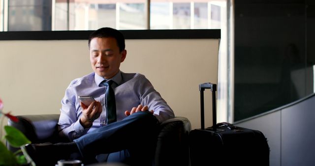 Businessman Sitting with Suitcase, Using Smartphone in Modern Office - Download Free Stock Images Pikwizard.com