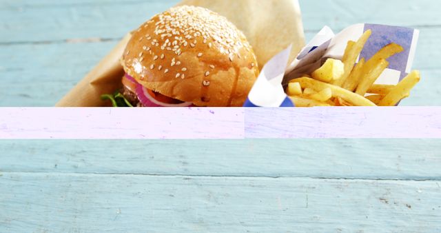A delicious burger paired with a side of golden fries is presented on a wooden surface, with copy space. Ideal for showcasing fast food cuisine or promoting a casual dining experience.