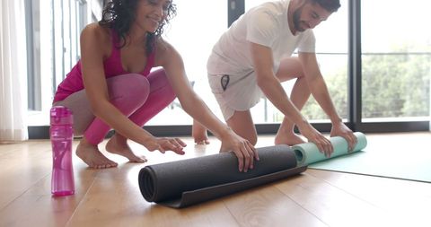 Couple Rolling Yoga Mats at Home