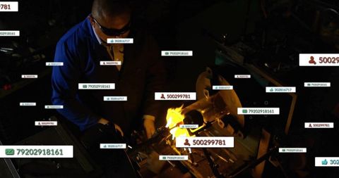 Industrial metalworker heating steel with torch in dark workshop with data tags and flame