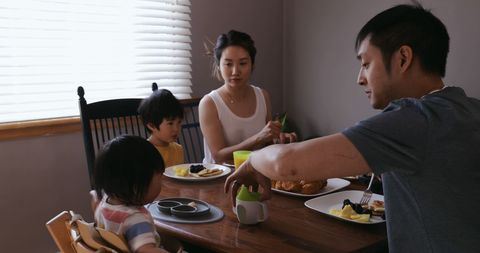 Asian Family Enjoying Meal Together with a Playful Toddler