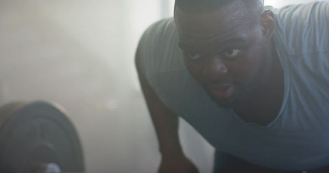 African weightlifter leaning over loaded barbell gripping plate sweat determination focus