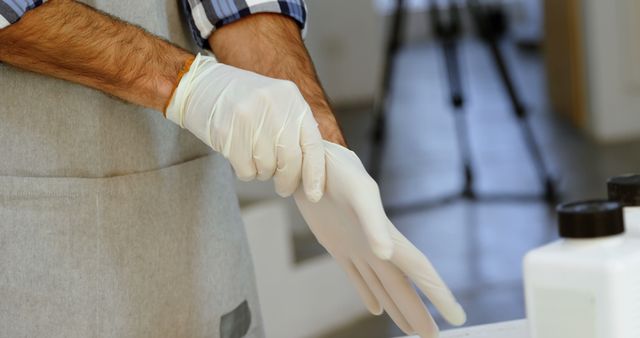 Person seen wearing yellow gloves and preparing for a task; such image can be ideal for demonstrations on lab safety, chemical handling, or medical scenarios. This can be used in training manuals, educational materials, or online articles focusing on the importance of protective gear and safety protocols in different settings.