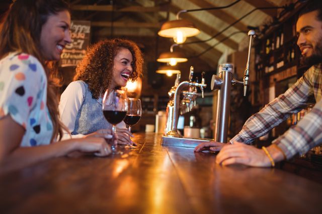Young women interacting with bartender at counter in pub    