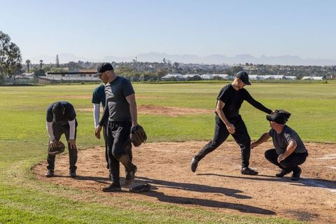 Baseball players practicing infield drill with crouched catcher reaching home plate