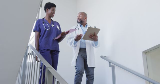 African american male and female doctors holding clipboard and talking at hospital - Download Free Stock Photos Pikwizard.com
